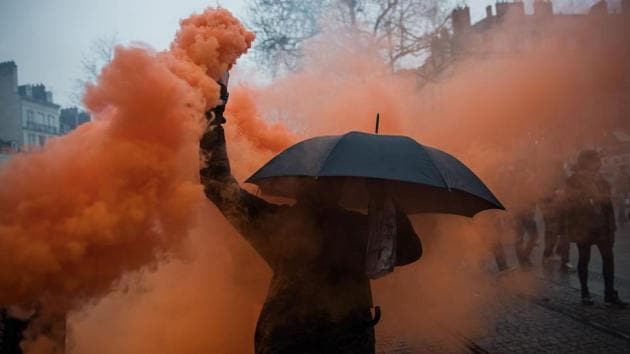 A demonstrator holds a coloured-smoke canister during a demonstration in Nantes as part of the sixth day of massive strike action over government's plans to overhaul the pension system. (Loic VENANCE / AFP)