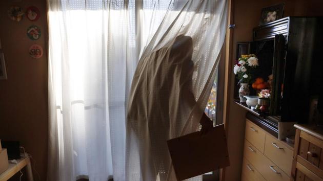 Toshihide Yoshida, a 71-year-old evacuee from the nuclear crisis-hit town of Futaba in Fukushima prefecture, walks out to the backyard of his home to dust off an old family photo in Kazo, Japan. The torch relay for the Tokyo Olympics will kick off in Fukushima, devastated almost nine years ago by an earthquake, tsunami and the subsequent meltdown of three nuclear reactors. (Jae C. Hong / AP)