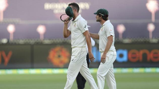 Australia's Josh Hazlewood (left) covers his face as he is consoled by team mate Joe Burnsafter he was injured during play in their cricket test in Perth, Australia, Friday, Dec. 13, 2019(AP)