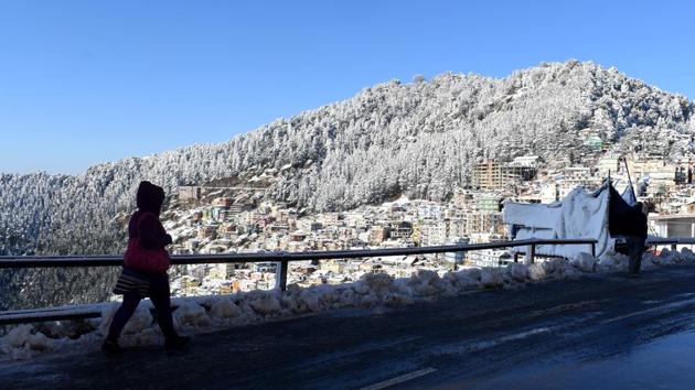 A woman is seen walking against the snow covered Jakhoo Hill, at Sanjauli, in Shimla, Himachal Pradesh. The heavy snowfall led to 200 vehicles being stranded at various places between Dhalli and Kufri. The Shimla district administration and police launched a joint operation to rescue 300 tourists stuck in the vehicles. (Deepak Sansta / HT Photo)