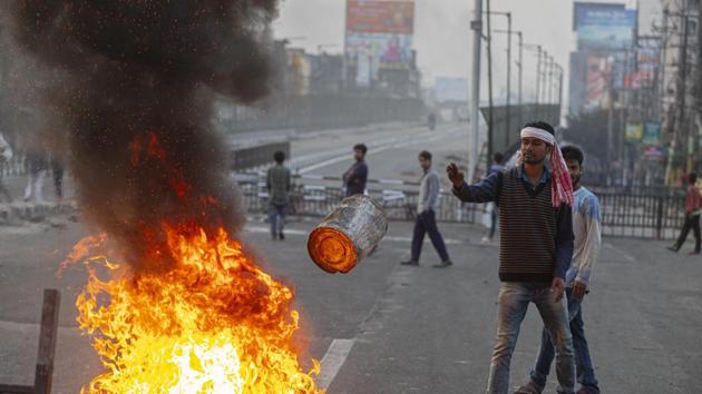 An Indian protester throws a tin onto a fire made to block traffic in Guwahati. Across the city, a phalanx of army and paramilitary personnel fanned out into arterial and narrow neighbourhood roads on Friday to contain any violence. (AP) An Indian protester throws a tin onto a fire made to block traffic in Guwahati. Across the city, a phalanx of army and paramilitary personnel fanned out into arterial and narrow neighbourhood roads on Friday to contain any violence. (AP)