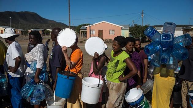 People stand in a queue holding plastic containers to fill water distributed by a humanitarian organization, Gift of the Givers, in the Bezuidenhoutville informal settlement. Rapid urbanisation and growing water consumption have placed a strain on water reserves and caused the coastal city of Cape Town to almost run dry in 2018. But the ongoing drought has compounded the situation. Dam levels dropped dangerously low in October, prompting President Cyril Ramaphosa to call for “drastic measures”. (Guillem Sartorio / AFP) People stand in a queue holding plastic containers to fill water distributed by a humanitarian organization, Gift of the Givers, in the Bezuidenhoutville informal settlement. Rapid urbanisation and growing water consumption have placed a strain on water reserves and caused the coastal city of Cape Town to almost run dry in 2018. But the ongoing drought has compounded the situation. Dam levels dropped dangerously low in October, prompting President Cyril Ramaphosa to call for “drastic measures”. (Guillem Sartorio / AFP)