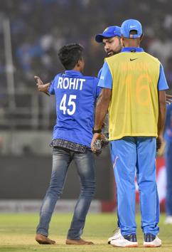 A pitch-invader interacts with Indian cricketer Rohit Sharma on the field. (PTI)