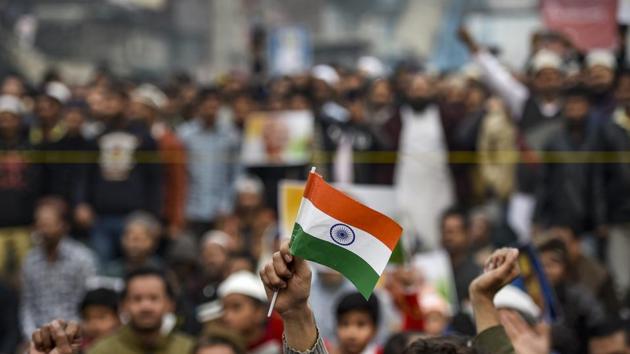 A protestor holds the national flag during a demonstration against the Citizenship Amendment Act (CAA) at Jamia Nagar. (PTI)