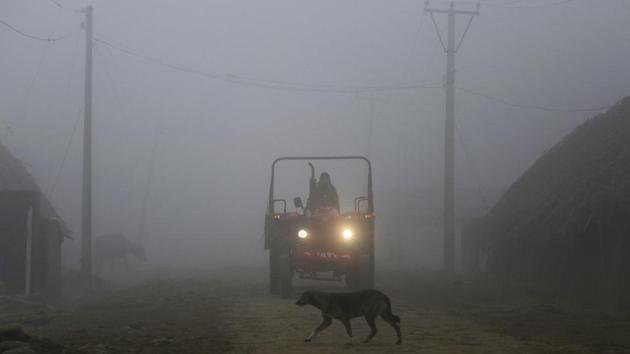 An Indian farmer rides a tractor through a dense fog on the outskirts of Jammu.(AP)