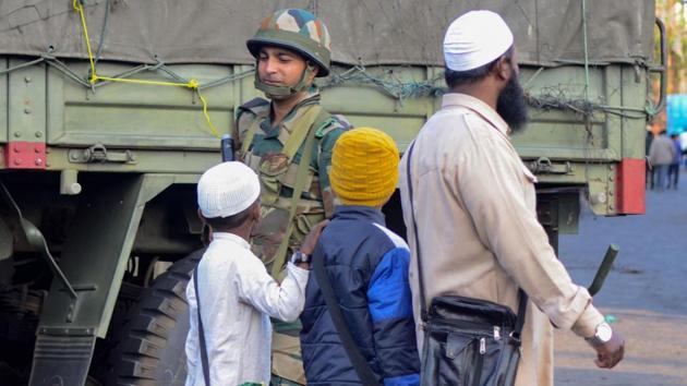 An army jawan guards as a man along with children walks past him, during relaxation of curfew, in Dibrugarh. (PTI) An army jawan guards as a man along with children walks past him, during relaxation of curfew, in Dibrugarh. (PTI)