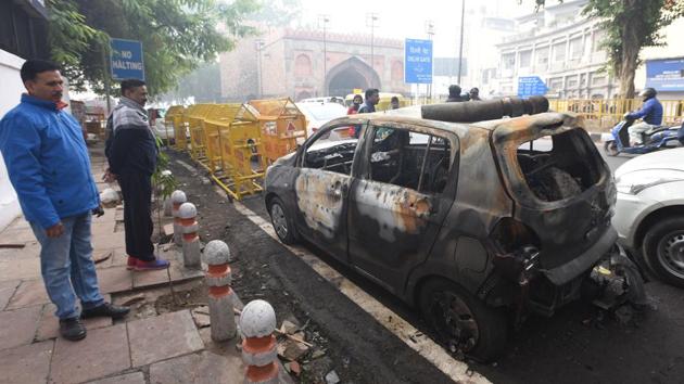 People look at a car that was allegedly burnt by protesters last evening, as demonstrations against the Citizenship Amendment Act (CAA) turned violent, outside the Deputy Commissioner of Police (DCP) office, Daryaganj, in Delhi. Both the police and residents said that those involved in the violence were “outsiders”. (Sonu Mehta / HT Photo)