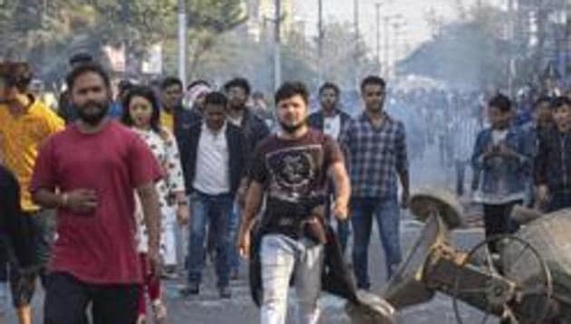 Protestors walk past a cement mixer lies toppled during Wednesday's protest against the Citizenship Amendment Bill (CAB) in Gauhati (AP) Protestors walk past a cement mixer lies toppled during Wednesday's protest against the Citizenship Amendment Bill (CAB) in Gauhati (AP)