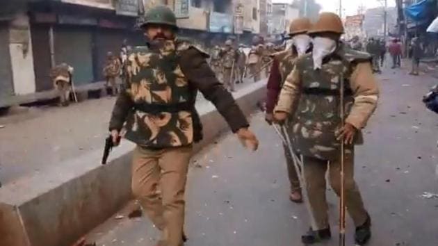 In the one-minute-37-second video, the policeman in riot gear is seen walking at the site of clashes with a revolver and his baton. He can be seen readying it and then walking to a corner and opening fire at protesters.(Videograb/Hindustan Times)