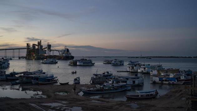 Boats at dusk in a port at Santarem, Para state. From Ruropolis, the Trans-Amazon and BR-163 run jointly westward over a bumpy 70 miles. During corn and soy harvests, 2,600 trucks pass through each day to and from the nearby Tapajos River. There, trucks pull into transshipment ports. Grain is loaded onto barges. After a downriver trip that takes days, it is poured into ships’ holds and dispatched across the world, largely to China. (Leo Correa / AP)