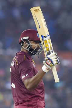West Indies batsman K. Pollard raises his bat to celebrate scoring fifty runs. (PTI)