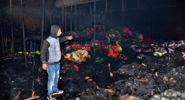 A man points at the burnt down warehouse of the factory at Focal Point in Ludhiana on Sunday. (HT PHOTO)