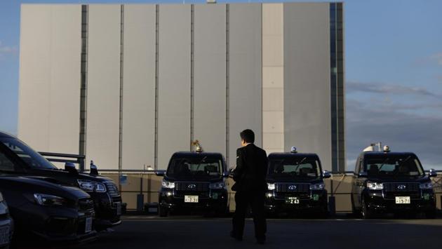 Norihito Arima walks to a taxi for an inspection. The company also has a booklet for drivers with 77 dos and don’ts: how and when to speak to passengers, taxi sanitation and opening doors for customers. There’s even one instructing drivers to keep both hands on the wheel. (Jae C. Hong / AP) 