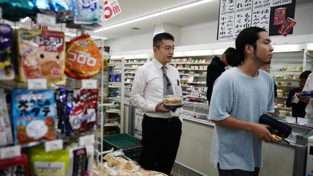 Norihito Arima waits in line at a convenient store to pay for his dinner. Japan has a low crime rate, which is good news for taxis drivers. But nocturnal Tokyo presents a heavy-drinking culture that can — literally — wind up in the laps of taxi drivers who work overnight. Norihito said he routinely offers a specially designed bag to unsteady customers. (Jae C. Hong / AP) 