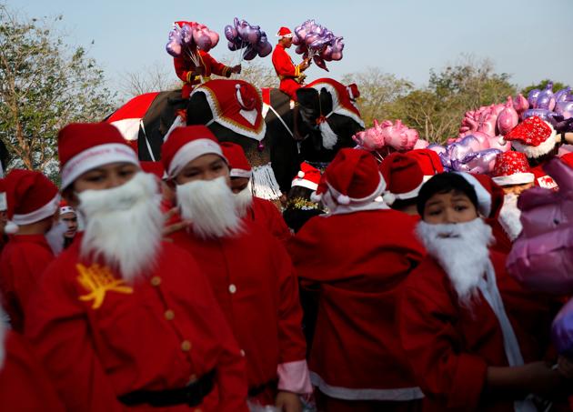 Students dressed in Santa hats stand near elephants wearing similar hats as the elephants distribute Christmas presents. (REUTERS)