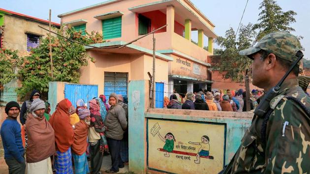 A security person stands guard as voters queue up to cast votes during the fifth phase of the Jharkhand Assembly elections, in Godda district, Friday, Dec. 20, 2019.(Photo: PTI)