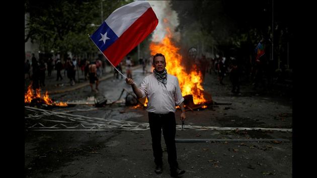 Alex Munoz Fuentes, 47, an accountant, with a Chilean flag in Santiago, Chile. “People in the world are tired of injustice,” said Fuentes. “I don’t want anything given for free,” “But I know that in Chile the institutions, the law and the constitution are made to abuse the working classes. I want a new deal”. “Hong Kong is similar, the authorities are not thinking about people’s well-being... I have a fraternal hug for them.” (Jorge Silva / REUTERS) Alex Munoz Fuentes, 47, an accountant, with a Chilean flag in Santiago, Chile. “People in the world are tired of injustice,” said Fuentes. “I don’t want anything given for free,” “But I know that in Chile the institutions, the law and the constitution are made to abuse the working classes. I want a new deal”. “Hong Kong is similar, the authorities are not thinking about people’s well-being... I have a fraternal hug for them.” (Jorge Silva / REUTERS)