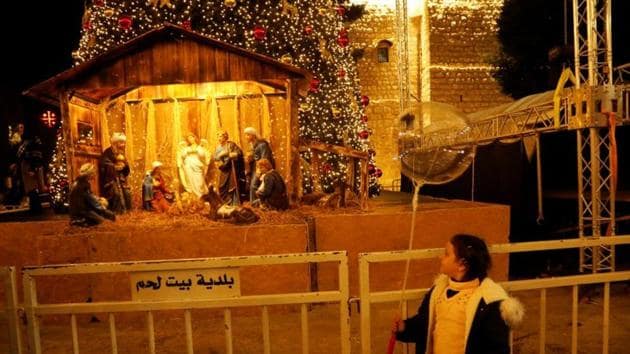 Christmas 2019: A girl looks at an artwork showing a nativity scene made of olive wood at Manger Square in Bethlehem. in the Israeli-occupied West Bank.(REUTERS)