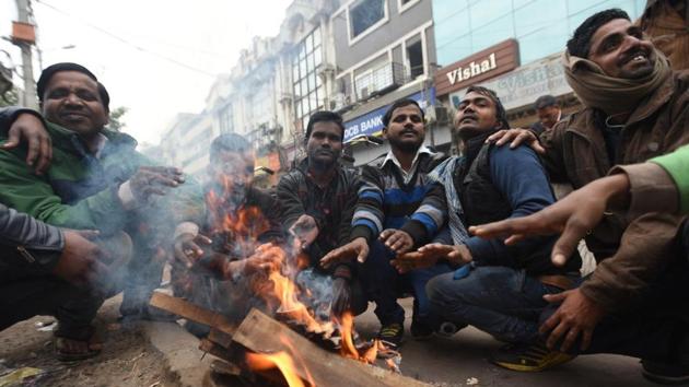 Labourers warm themselves around a bonfire in East Delhi on a cold winter morning, on Tuesday. (Sonu Mehta/Hindustan Times) Labourers warm themselves around a bonfire in East Delhi on a cold winter morning, on Tuesday. (Sonu Mehta/Hindustan Times)