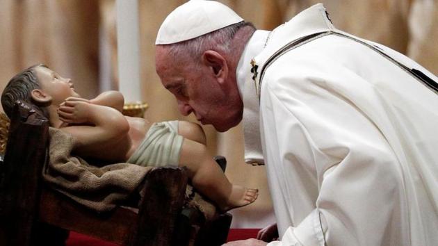 Pope Francis kisses a statue of baby Jesus as he leads the Christmas Eve mass in St. Peter's Basilica at the Vatican on December 24.(REUTERS)