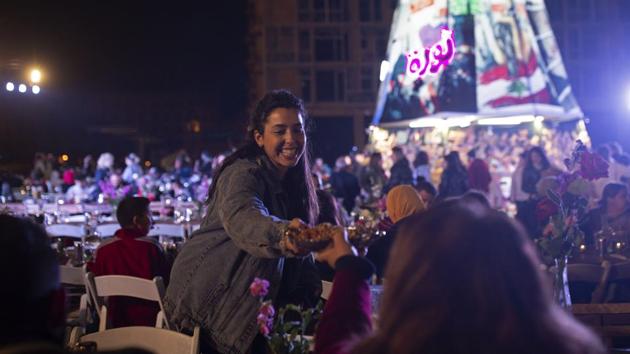 A volunteer serves food at a public Christmas dinner as part of an initiative to help those in need, at Martyrs’ Square, where anti-government activists are encamped in Beirut, Lebanon. The country is entering its third month of protests. (Maya Alleruzzo / AP) A volunteer serves food at a public Christmas dinner as part of an initiative to help those in need, at Martyrs’ Square, where anti-government activists are encamped in Beirut, Lebanon. The country is entering its third month of protests. (Maya Alleruzzo / AP)