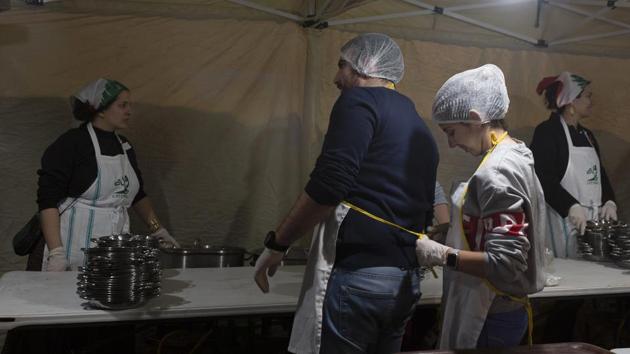 A woman ties an apron on a fellow volunteer before they serve a public Christmas dinner at Martyrs’ Square. To ease communication between people, a group of web developers created an app, Khayyak or Your Brother, to coordinate between those who want to help and those in need. “Don’t lose hope, you are not alone,” the advertisement for the app said. (Maya Alleruzzo / AP) A woman ties an apron on a fellow volunteer before they serve a public Christmas dinner at Martyrs’ Square. To ease communication between people, a group of web developers created an app, Khayyak or Your Brother, to coordinate between those who want to help and those in need. “Don’t lose hope, you are not alone,” the advertisement for the app said. (Maya Alleruzzo / AP)