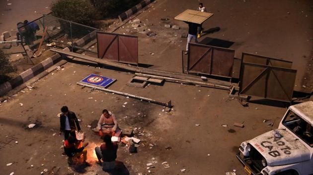 Local residents sit around a bonfire to keep themselves warm as they block a road during a protest. (Anushree Fadnavis / REUTERS)