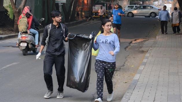 Volunteers of Pune Ploggers collecting garbage at Baner Pashan link road in Pune.(Milind Saurkar/HT Photo)