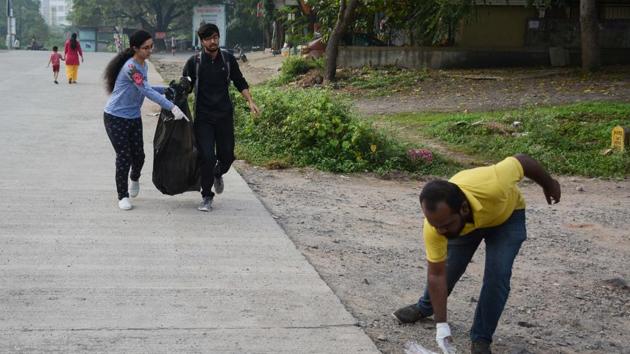 Volunteers of Pune Ploggers collecting garbage at Baner Pashan link road in Pune.(Milind Saurkar/HT Photo)