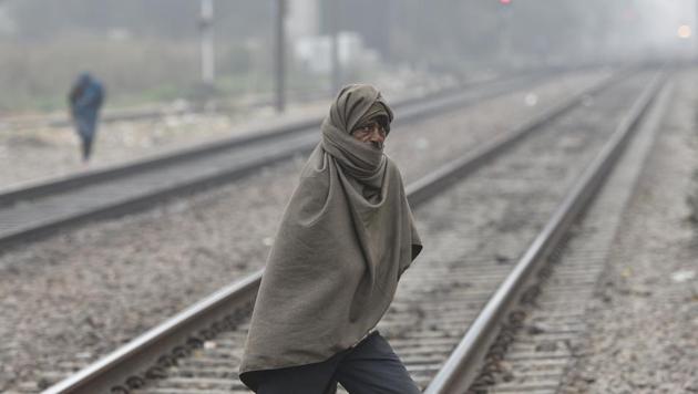 A man wrapped in a shawl crosses a railway track oh Thursday as the national capital witnesses intense cold conditions.(Burhaan Kinu/HT Photo)