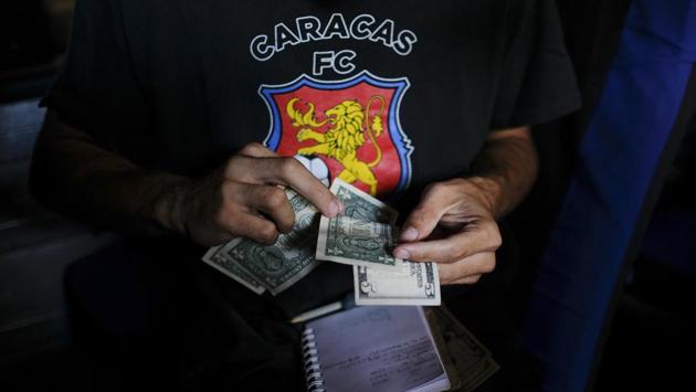 A member of Red Demons counts US currency for transportation from Caracas to Lara state to attend a soccer match between Deportivo Lara and Caracas FC, in Caracas. The club's die-hard fans do not miss games, even when money is tight as their homeland experiences its worst ever economic slump, and one of the most serious in Latin America. (Matias Delacroix / AP)