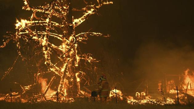 NSW Rural Fire Service crew fight the Gospers Mountain Fire as it impacts a property at Bilpin, New South Wales, Australia. Prime Minister Scott Morrison on Sunday apologised for taking a family vacation in Hawaii as deadly bushfires raged across several states, destroying homes and claiming the lives of two volunteer firefighters. (Dan Himbrechts / AP) NSW Rural Fire Service crew fight the Gospers Mountain Fire as it impacts a property at Bilpin, New South Wales, Australia. Prime Minister Scott Morrison on Sunday apologised for taking a family vacation in Hawaii as deadly bushfires raged across several states, destroying homes and claiming the lives of two volunteer firefighters. (Dan Himbrechts / AP)