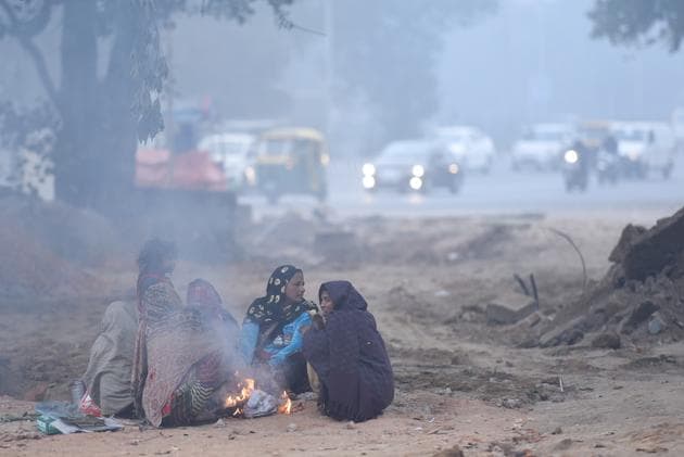 Women and children warm themselves around a bonfire at Safdarjung in New Delhi.(Sanchit Khanna/HT PHOTO)