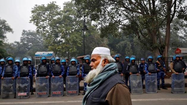 A Muslim man walks past Rapid Action Force personnel during a protest against a new citizenship law, in Delhi.(Photo: Reuters) A Muslim man walks past Rapid Action Force personnel during a protest against a new citizenship law, in Delhi.(Photo: Reuters)