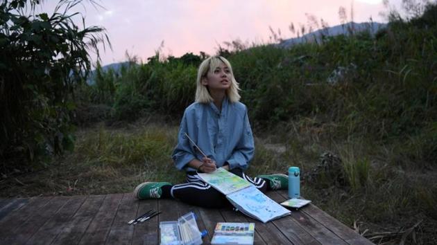 Chen Yan looks up as she paints on a hill during sunset at AnotherCommunity in Guanzhong village, Fuzhou, Fujian province, China. The community was set by Tang Guanhua, 30, and his wife, Xing Zhen, 35, in late 2015. (Tingshu Wang / REUTERS)