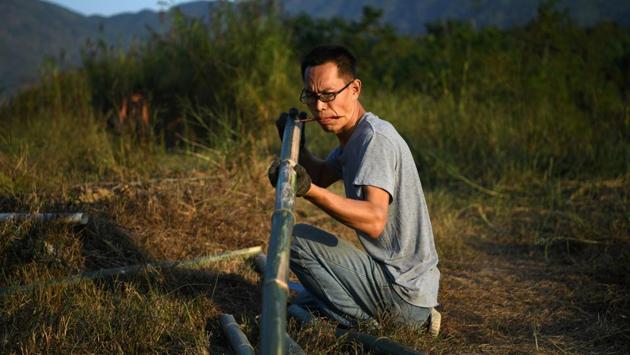 Da Wang mounts freshly chopped bamboo to make a rack at his farm, at AnotherCommunity. A newspaper reported in 2018 that a young woman had moved into the Zhongnan mountains in Shanxi province seeking a hermit life. Her story went viral on social media after she was forcibly evicted. (Tingshu Wang / REUTERS)