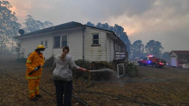 A firefighter speaks to a resident trying to hose down her home in the hope of saving it from nearby bushfires around the town of Nowra. In some places the blazes were so intense, the smoke so thick and the fire-provoked dry lightning storms so severe that aerial reconnaissance and water-bombing had to be halted, the New South Wales Rural Fire Service said to AFP. (Saeed Khan/AFP) A firefighter speaks to a resident trying to hose down her home in the hope of saving it from nearby bushfires around the town of Nowra. In some places the blazes were so intense, the smoke so thick and the fire-provoked dry lightning storms so severe that aerial reconnaissance and water-bombing had to be halted, the New South Wales Rural Fire Service said to AFP. (Saeed Khan/AFP)