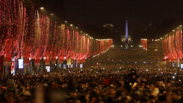 People gather to attend the fireworks over the Arc de Triomphe as they celebrate the New Year on the Champs Elysees, in Paris, France. (Christophe Ena / AP) People gather to attend the fireworks over the Arc de Triomphe as they celebrate the New Year on the Champs Elysees, in Paris, France. (Christophe Ena / AP)