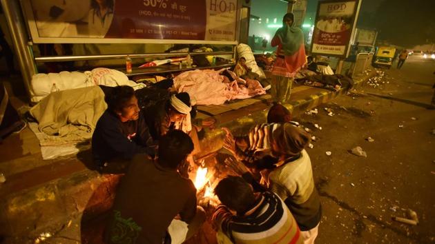 People gather around a bonfire near a bus shelter on a cold winter night near AIIMS. “The doctors have asked me to stay warm, but it’s not possible here. Many of us here use tarpaulin sheets, as they are waterproof and helps keep the dew away,” said Satish Singh, who had come to Delhi for getting treatment for his liver ailment. He has been living here for over a month. (Sanjeev Verma/HT Photo) People gather around a bonfire near a bus shelter on a cold winter night near AIIMS. “The doctors have asked me to stay warm, but it’s not possible here. Many of us here use tarpaulin sheets, as they are waterproof and helps keep the dew away,” said Satish Singh, who had come to Delhi for getting treatment for his liver ailment. He has been living here for over a month. (Sanjeev Verma/HT Photo)