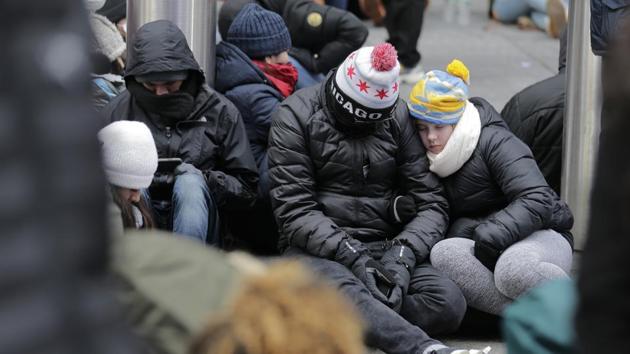 People rest on the ground as they wait for midnight at Times Square in New York on New Year's Eve. (Seth Wenig / AP) People rest on the ground as they wait for midnight at Times Square in New York on New Year's Eve. (Seth Wenig / AP)