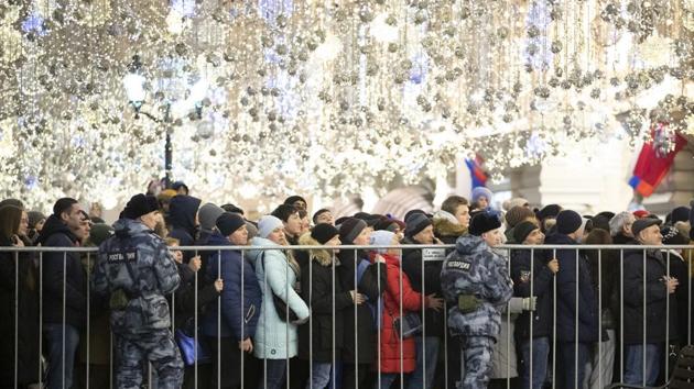People stand under Christmas decorations as they wait in a long queue to enter Red Square to celebrate New Year in Moscow, Russia. (Denis Tyrin / AP) People stand under Christmas decorations as they wait in a long queue to enter Red Square to celebrate New Year in Moscow, Russia. (Denis Tyrin / AP)