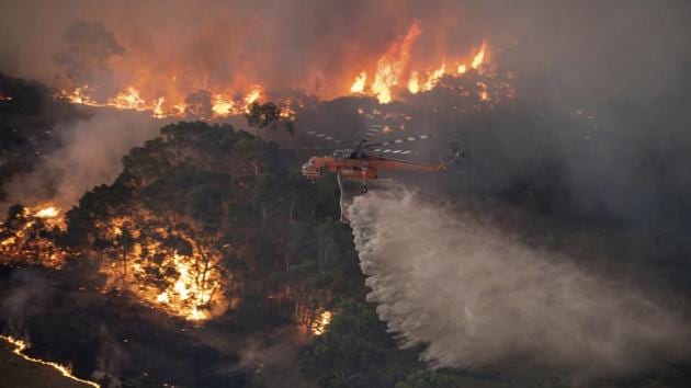 A helicopter tackles a wildfire in East Gippsland, Victoria state, Australia. Wildfires burning across Australia's two most-populous states trapped residents of a seaside town in apocalyptic conditions on Tuesday and were feared to have destroyed many properties and caused fatalities. (AP) A helicopter tackles a wildfire in East Gippsland, Victoria state, Australia. Wildfires burning across Australia's two most-populous states trapped residents of a seaside town in apocalyptic conditions on Tuesday and were feared to have destroyed many properties and caused fatalities. (AP)