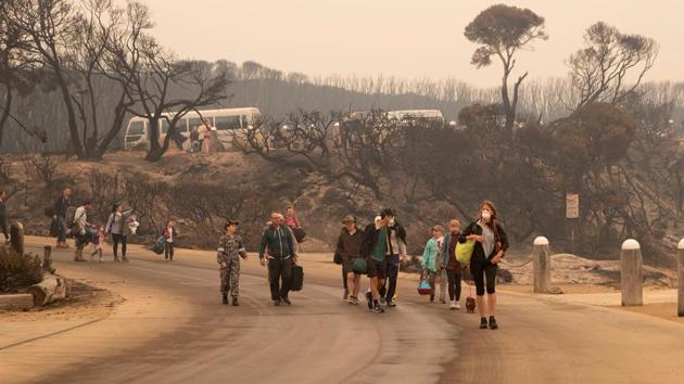 People walking to a beach before being evacuated from Mallacoota, Victoria state to HMAS Choules, during bushfire relief efforts. Catastrophic blazes ripped through the country’s south-east on New Year’s Eve, killing at least 8 people and stranding holidaymakers. (Helen Frank/ROYAL AUSTRALIAN NAVY/AFP) People walking to a beach before being evacuated from Mallacoota, Victoria state to HMAS Choules, during bushfire relief efforts. Catastrophic blazes ripped through the country’s south-east on New Year’s Eve, killing at least 8 people and stranding holidaymakers. (Helen Frank/ROYAL AUSTRALIAN NAVY/AFP)