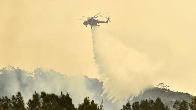 A helicopter drops water on a bushfire outside of Batemans Bay in New South Wales. New South Wales (NSW) Premier Gladys Berejiklian declared a seven-day state of emergency that allows for forced evacuations beginning Friday, for the third time in Australia’s most populated region this fire season. (Peter Parks/AFP) A helicopter drops water on a bushfire outside of Batemans Bay in New South Wales. New South Wales (NSW) Premier Gladys Berejiklian declared a seven-day state of emergency that allows for forced evacuations beginning Friday, for the third time in Australia’s most populated region this fire season. (Peter Parks/AFP)
