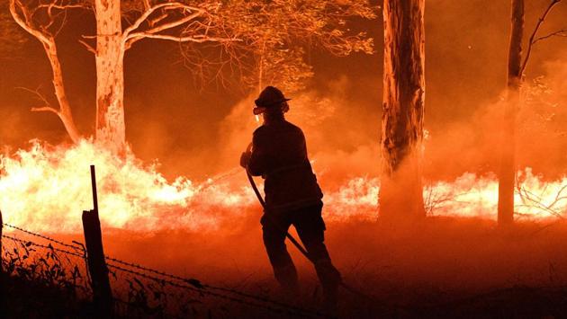 A firefighter hosing down trees and flying embers in an effort to secure nearby houses from bushfires near the town of Nowra in New South Wales. NSW Transport Minister Andrew Constance called it the “largest evacuation of people out of the region ever”, with a queue of cars stretching along the highway towards Sydney as thousands flee the area. One driver told AFP it had taken her three hours to travel just 50km. (Saeed Khan/AFP) A firefighter hosing down trees and flying embers in an effort to secure nearby houses from bushfires near the town of Nowra in New South Wales. NSW Transport Minister Andrew Constance called it the “largest evacuation of people out of the region ever”, with a queue of cars stretching along the highway towards Sydney as thousands flee the area. One driver told AFP it had taken her three hours to travel just 50km. (Saeed Khan/AFP)
