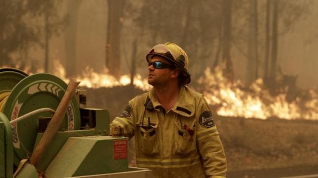 A Forest Corporation worker manages a fire hose as he battles a fire near Moruya, Australia, Saturday, Jan. 4, 2020. Australia's Prime Minister Scott Morrison called up about 3,000 reservists as the threat of wildfires escalated Saturday in at least three states with two more deaths, and strong winds and high temperatures were forecast to bring flames to populated areas including the suburbs of Sydney. (AP) A Forest Corporation worker manages a fire hose as he battles a fire near Moruya, Australia, Saturday, Jan. 4, 2020. Australia's Prime Minister Scott Morrison called up about 3,000 reservists as the threat of wildfires escalated Saturday in at least three states with two more deaths, and strong winds and high temperatures were forecast to bring flames to populated areas including the suburbs of Sydney. (AP)