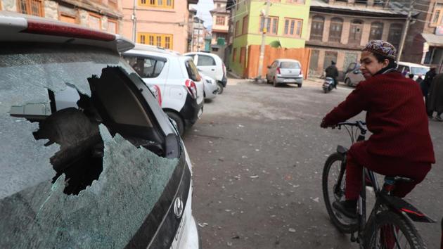 A cyclist looks at the damaged windshield of a vehicle near the site of a grenade explosion in the downtown area of Srinagar, Jammu and Kashmir. (Waseem Andrabi / HT Photo)