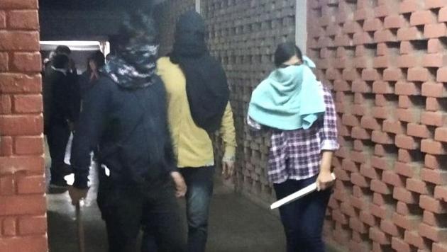 Masked miscreants armed with sticks roaming inside JNU campus in New Delhi on Sunday.(PTI PHOTO.)