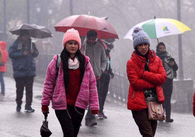 Locals and tourists making their way through light rain on The Ridge in Shimla on Monday.(Deepak Sansta /HT)