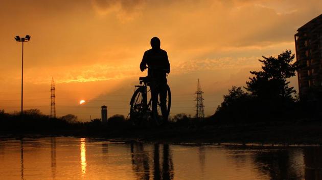 A cyclist on his way as the sun sets on the outskirts of Mohali on Wednesday. (Gurminder Singh/HT)